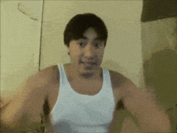 a man in a white tank top is making a face