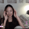 a woman is sitting in front of a computer screen with her hands on her head .