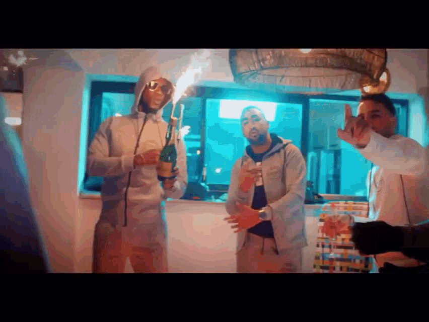 a group of men are standing in a room and one of them is wearing a hooded jacket