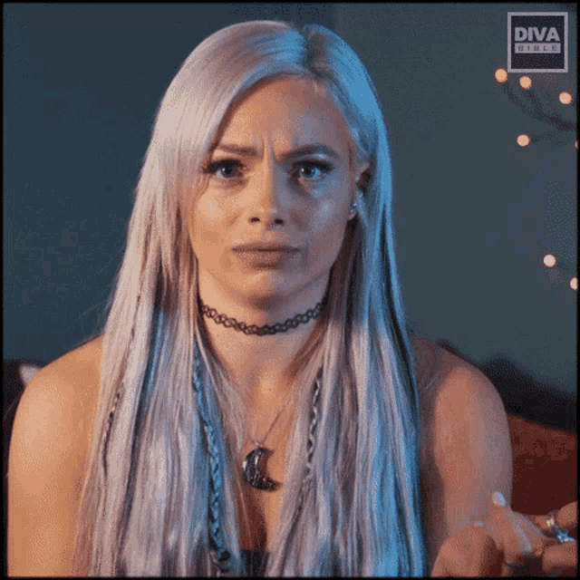 a woman with a choker and a diva shield logo on her face