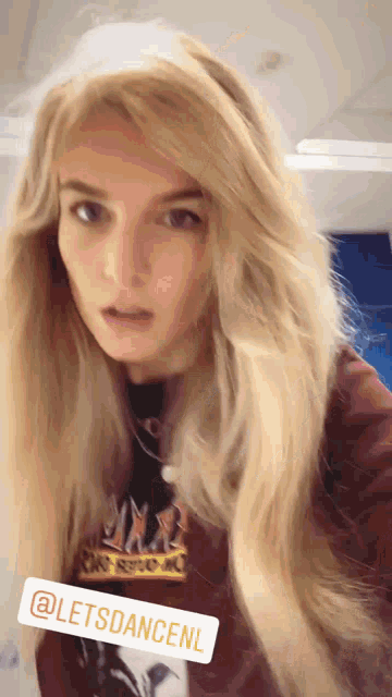 a woman with blonde hair is wearing a red jacket and a black shirt that says ' letsdancenl '
