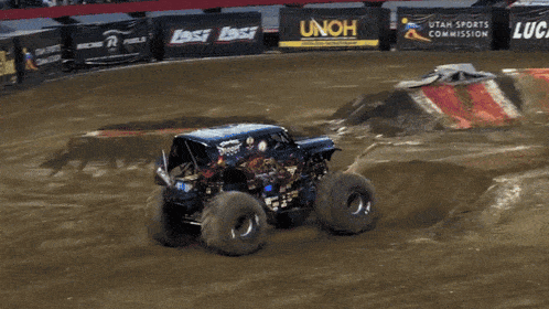 a monster truck is doing a trick in front of a sign that says ' gas oil '