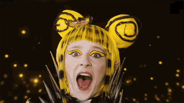 a woman is wearing a yellow wig and a black costume with spikes