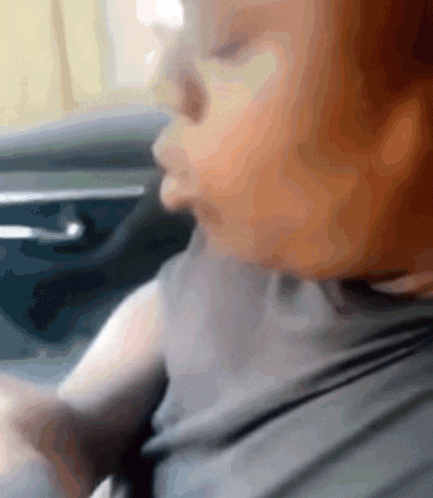 a close up of a person 's face while sitting in a car