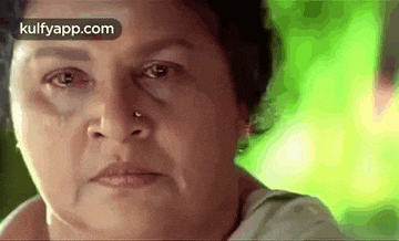 a close up of a woman 's face with a nose ring and tears coming out of her eyes .