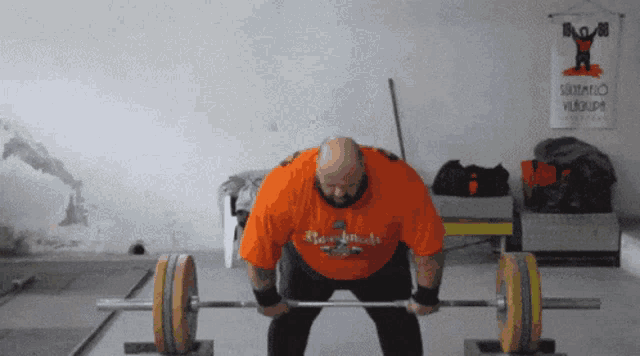 a man in an orange shirt is lifting a barbell in front of a sign that says ' salomon '