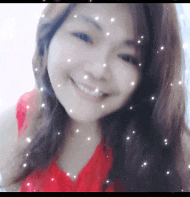 a woman in a red shirt is smiling with snow falling around her face
