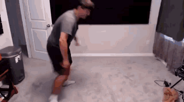 a man is dancing in a living room in front of a tv .