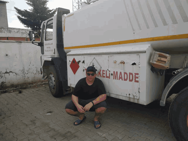 a man is squatting in front of a truck that says keli-madde