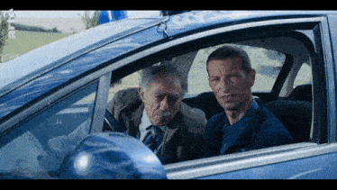 two men are sitting in a car with a blue light on top of it
