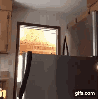a stainless steel refrigerator in a kitchen with a gifs.com watermark on the bottom right