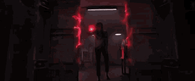 a woman is standing in a dark room with a red light coming out of her hands .