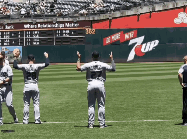 baseball players standing on a field with a 7up advertisement on the wall behind them