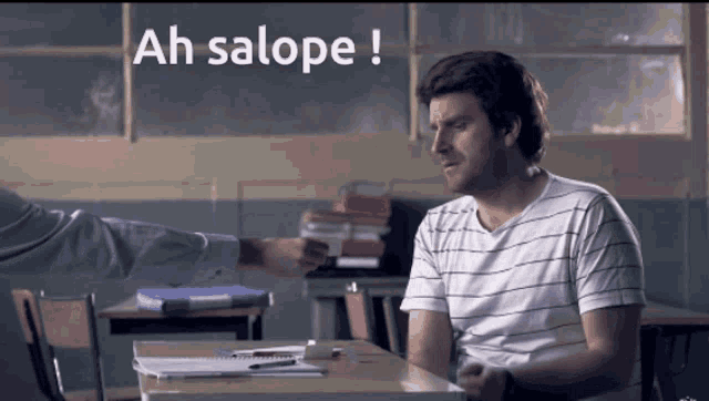 a man sitting at a desk with ah salope written on the top