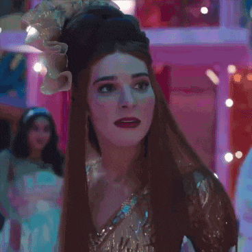 a woman with long red hair and a flower in her hair is wearing a gold dress .