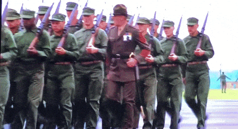 a group of soldiers marching in a parade with a man in the middle holding a book