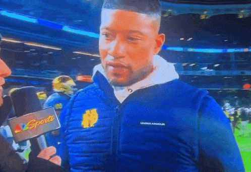 a man wearing a blue under armour vest is smiling