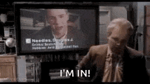 a bald man in a suit and tie is standing in front of a television screen and saying `` i 'm in '' .