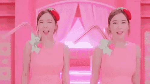 two women in pink dresses with strawberries in their hair are standing next to each other .