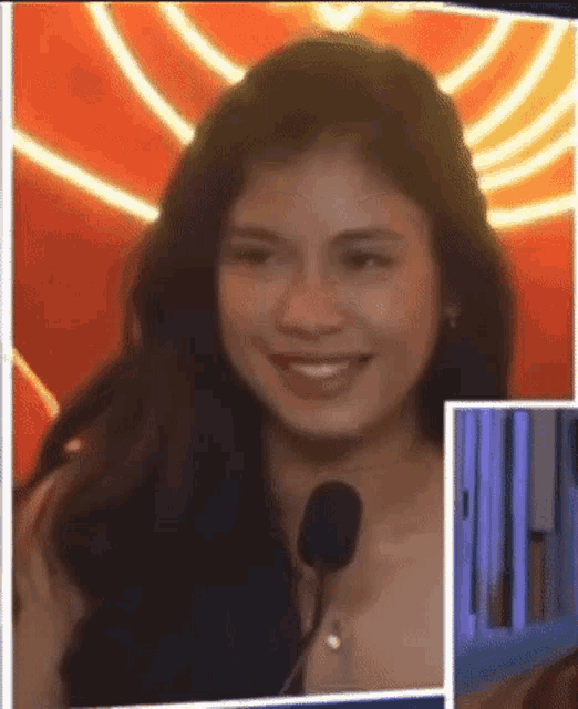 a woman is smiling while talking into a microphone .