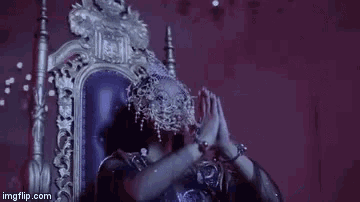 a woman is sitting on a throne wearing a mask and a veil .