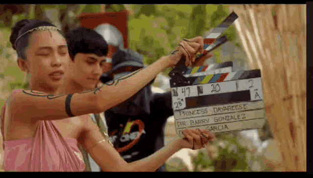 a woman in a pink dress is holding a clapper board that says princess davarese on it
