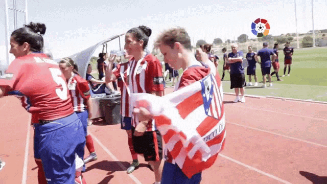a group of people standing on a track with one wearing a jersey that says ' atletico madrid '