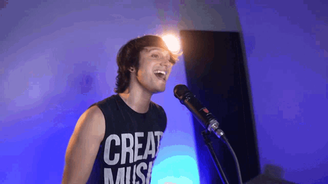 a man singing into a microphone wearing a black shirt that says great music