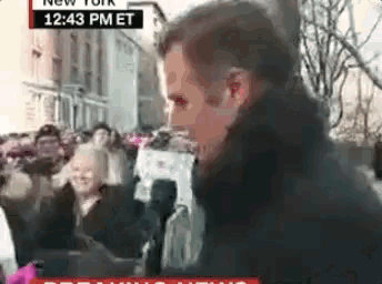 a man is standing in front of a crowd of people with a sign that says ' new york ' on it .