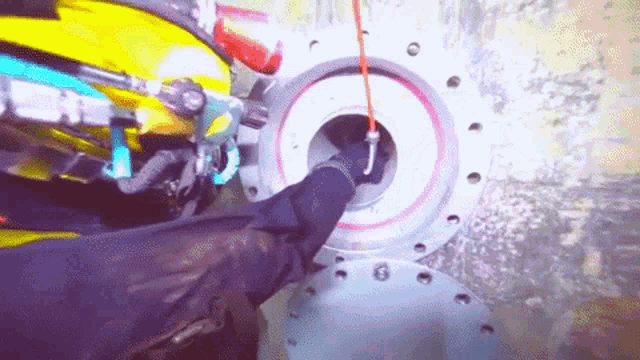 a person wearing a helmet and gloves is working on a machine