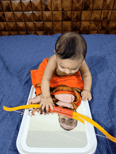 a baby is playing with a toy bow and arrow in front of a mirror