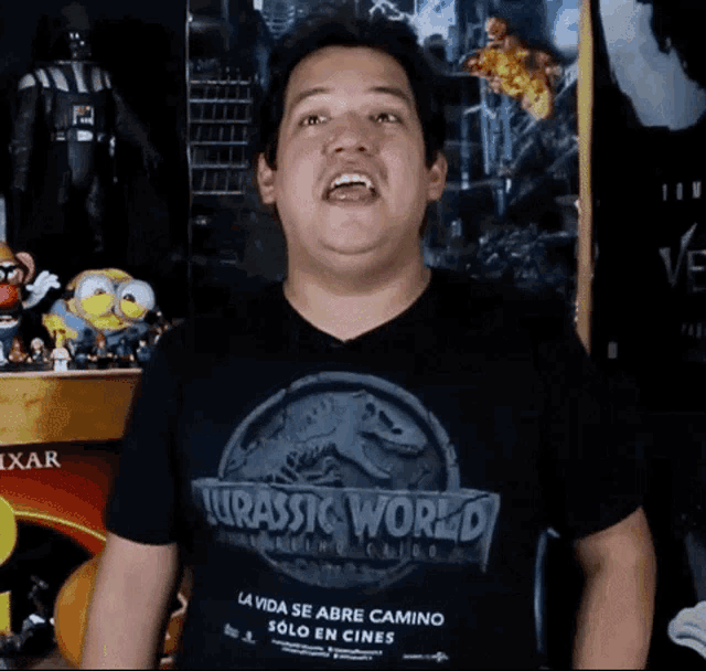 a man is wearing a jurassic world t-shirt and making a funny face