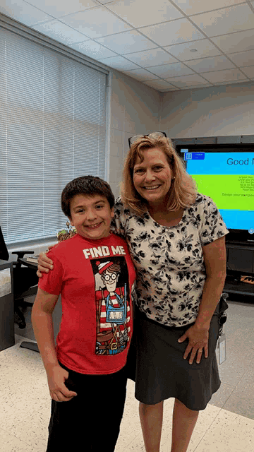 a boy wearing a red shirt that says find me poses with a woman