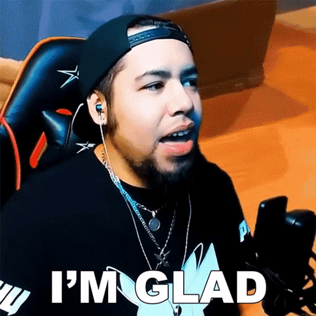 a man with a beard is sitting in front of a microphone and says i 'm glad .