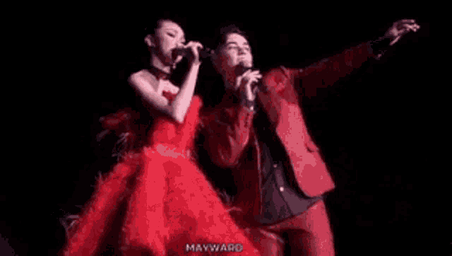 a woman in a red dress is standing next to a man in a red suit .
