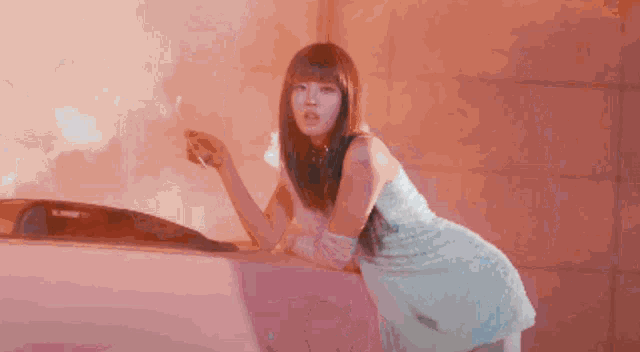 a woman in a white dress is standing next to a pink car
