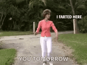 a woman is walking down a path with the words `` i farted here you tomorrow '' written on the side .