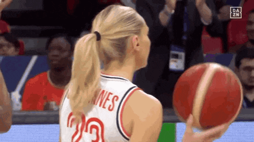 a woman in a ponytail is holding a basketball on a court .