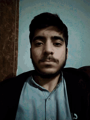 a man with a beard wearing a blue shirt and a black jacket