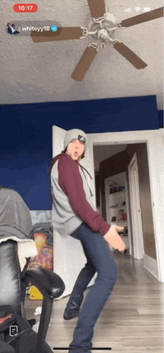 a person is dancing in a room with a ceiling fan and the time 10:17