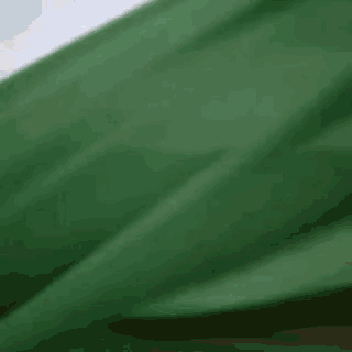 a green cloth is blowing in the wind with a blue sky in the background