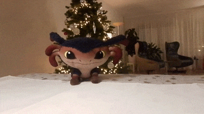 a stuffed animal with horns is sitting on a table in front of a christmas tree