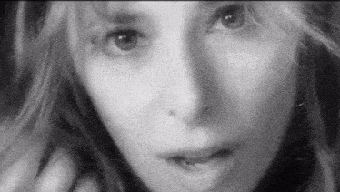 a black and white photo of a woman 's face looking at the camera .