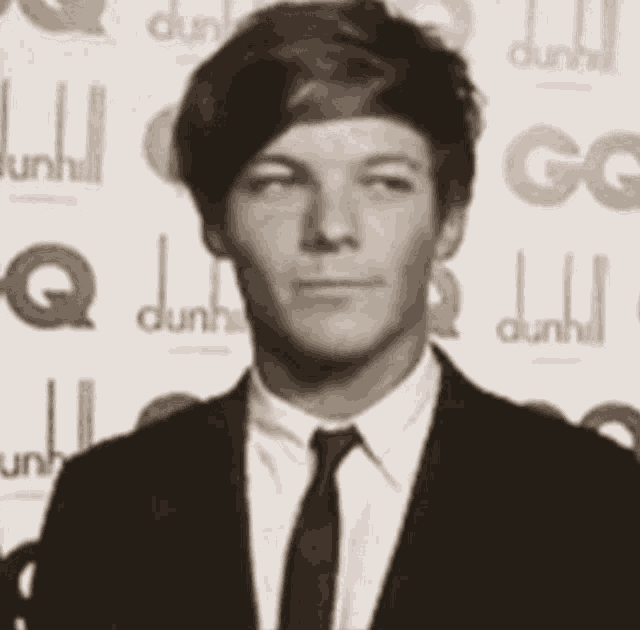 a man in a suit and tie is standing in front of a dunhill logo