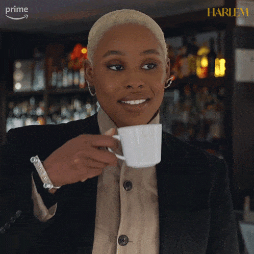 a woman holding a cup of coffee in front of a bar that says harlem