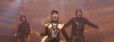 a group of people are dancing on a stage with a yellow light behind them