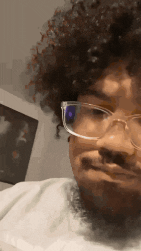 a man with curly hair is wearing glasses and making a funny face
