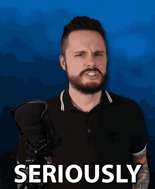 a man with a beard is standing in front of a microphone and the word seriously is on the blue background