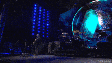 a man playing a guitar on a stage with a gifrun.com watermark