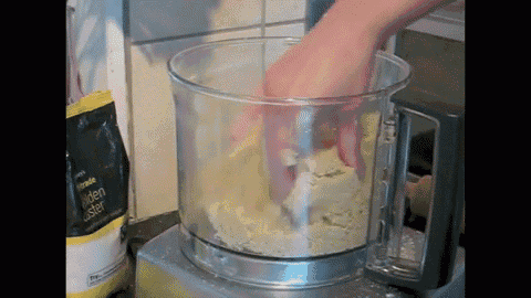 a person is mixing a dough in a food processor with a bag of wheat star in the background